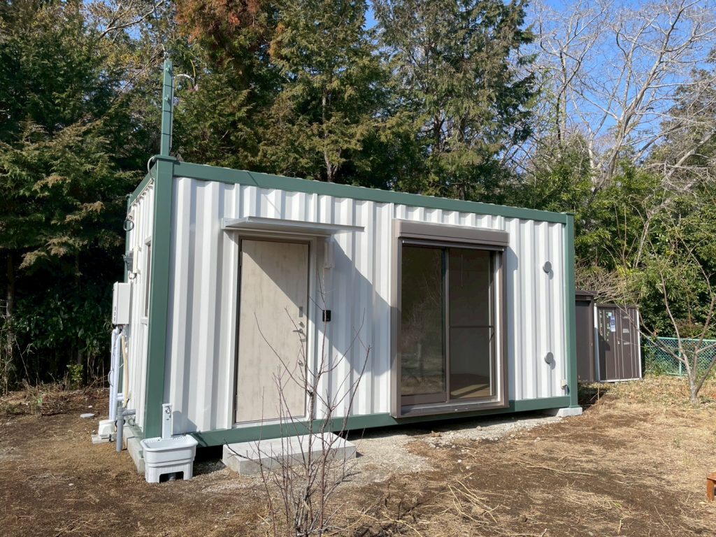20ftコンテナを１台使用した別荘。
長辺に玄関・掃き出し窓があります。
グリーンとライトグレーのバイカラー塗装。