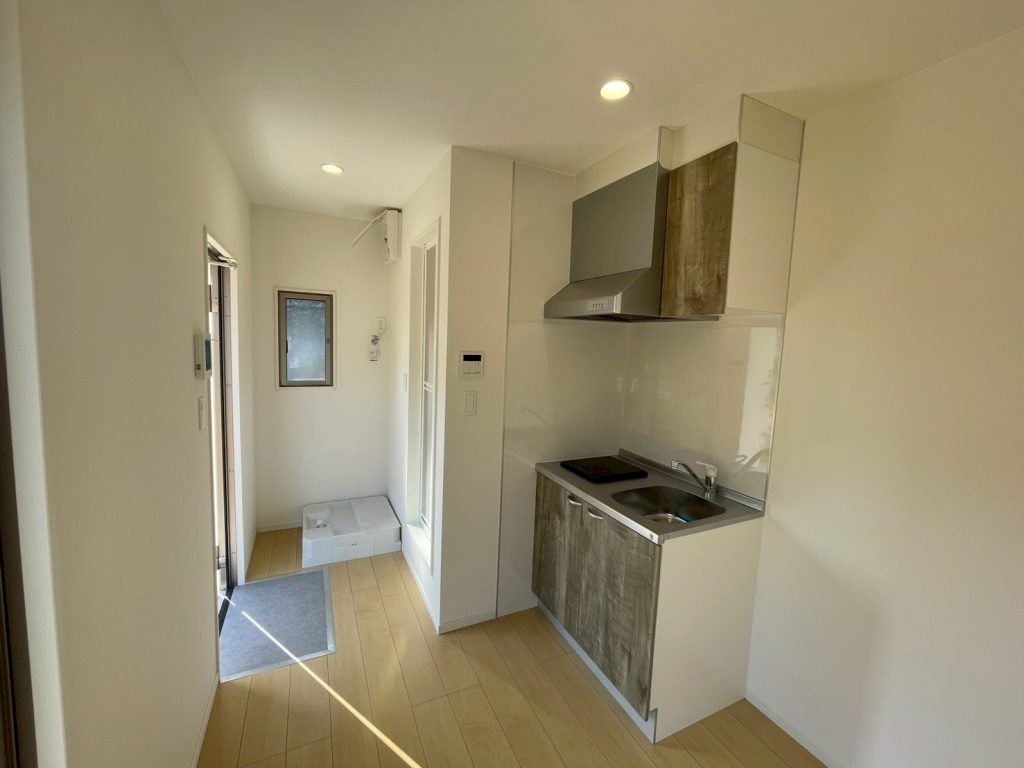 玄関正面に３点ユニットバスの入り口
ユニットバスの横には幅900㎜の木目柄のミニキッチン